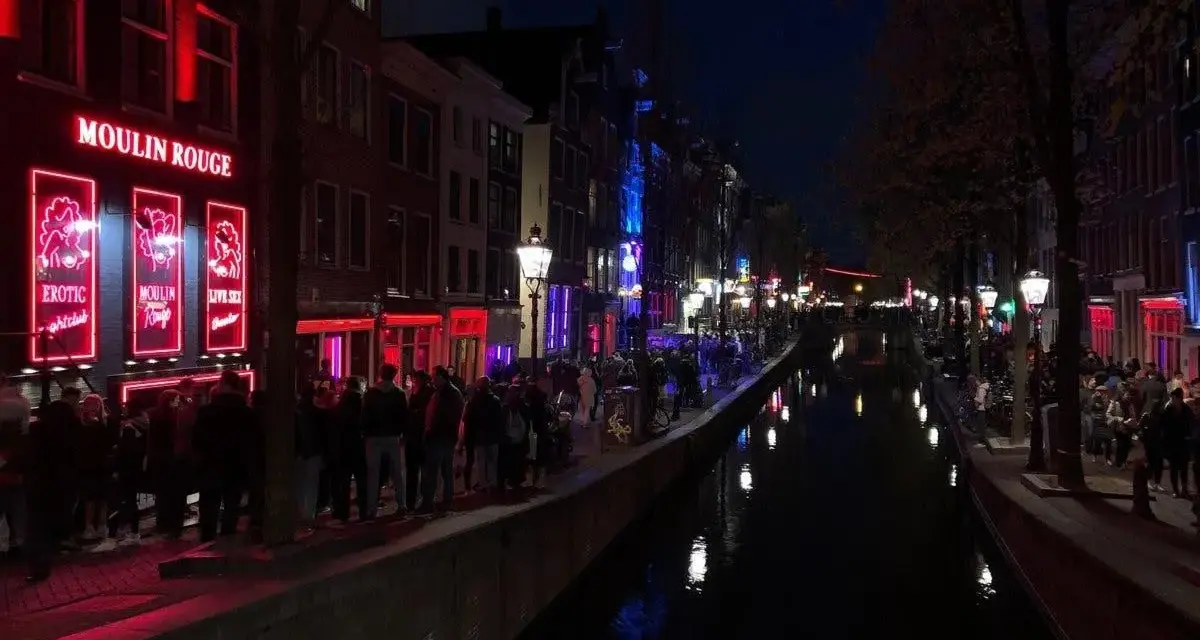 Nocna czerwona ulica Amsterdamu z kanałem i neonami.