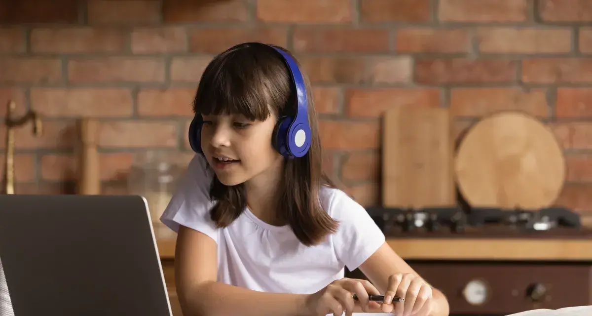 Dziewczynka w słuchawkach uczy się z laptopem. Jej liceum online to przyszłość edukacji.