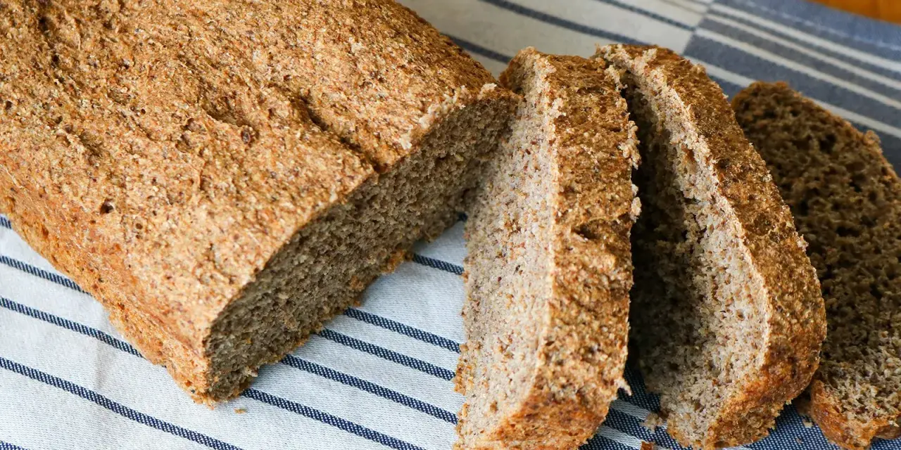 Ein frisch gebackenes vollkornbrot mit hefe, aufgeschnitten auf einem gestreiften Tuch.