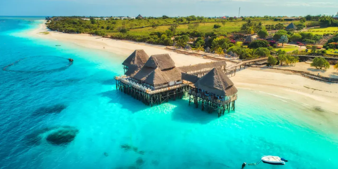 Rajskie plaże i turkusowa woda, idealne tanzania atrakcje. Domki na palach w tropikalnym otoczeniu.