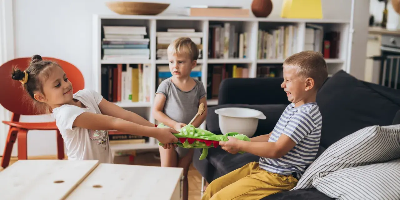Zwei Kinder im **Streit mit Schwester** um ein Stofftier. Ein kleiner Junge schaut zu.
