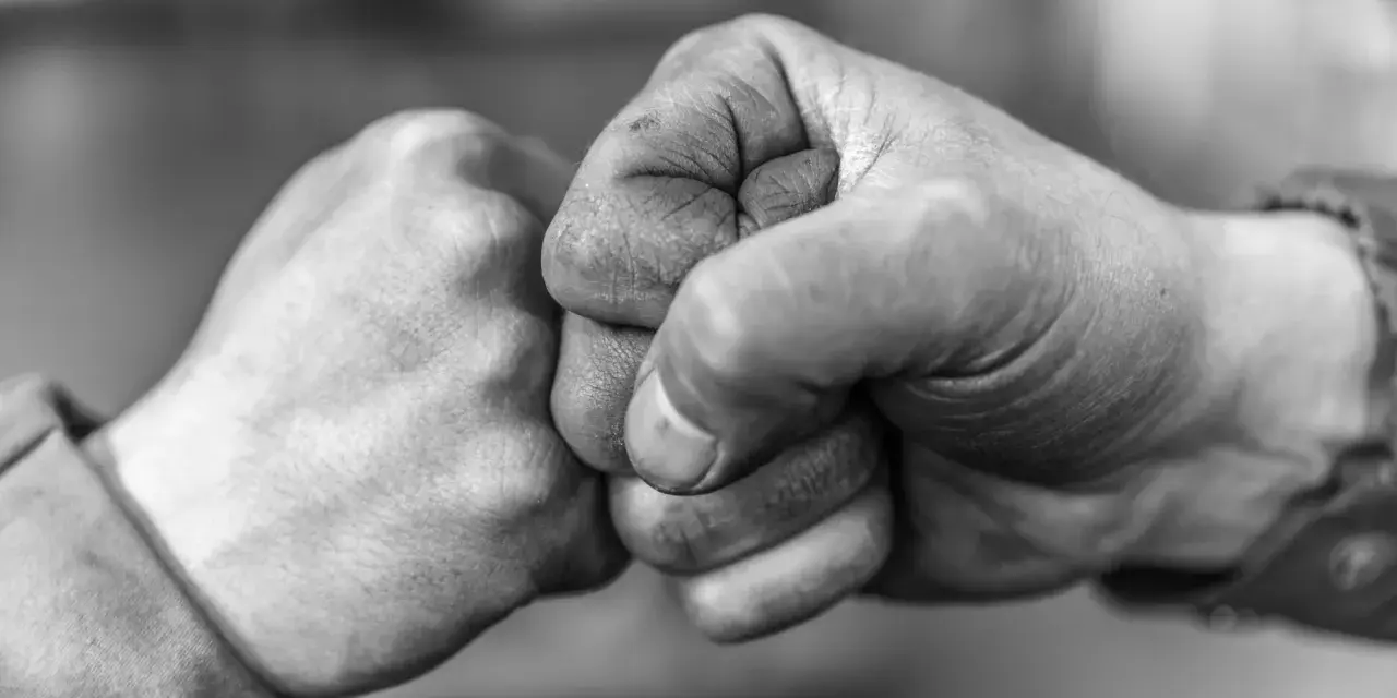 Zwei Fäuste stoßen zusammen, ein Zeichen von Solidarität und Verbundenheit.