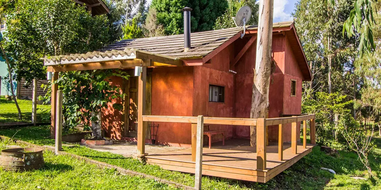 Il progetto di una piccola casa di campagna, con tetto spiovente, camino e un albero che attraversa la struttura.