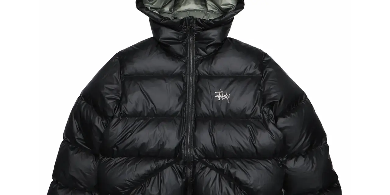 Piumino nero Stussy con cappuccio e logo bianco sul petto. Perfetto per affrontare il freddo con stile.