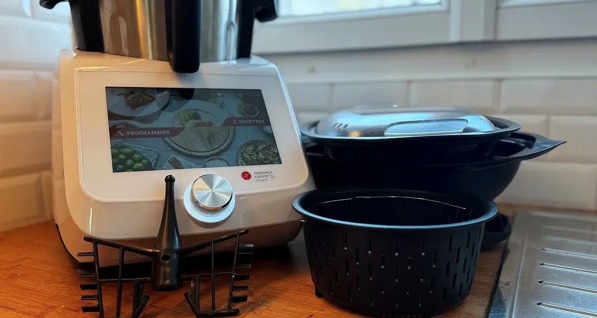 Robot culinaire Monsieur Cuisine Smart prêt à préparer une recette. Accessoires et bols empilés à côté.