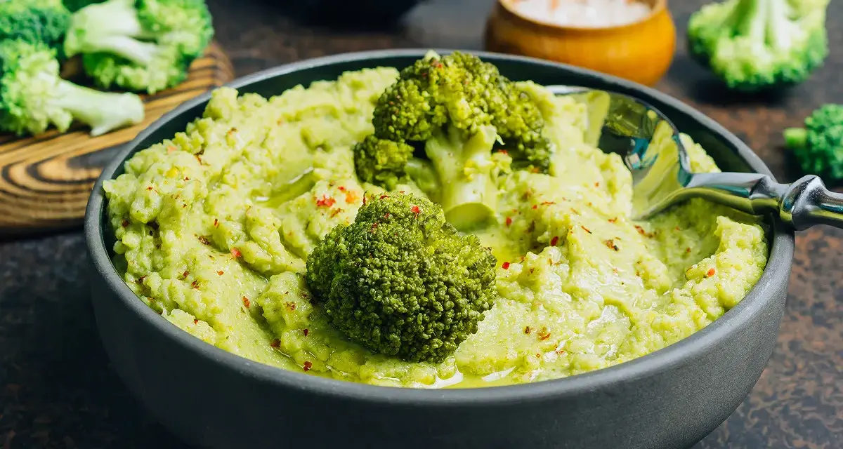 Un bol de purée de brocolis onctueuse, garni de fleurettes de brocolis et d'épices rouges. Un délice vert et sain.