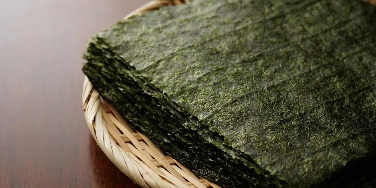 Feuilles d'algue nori empilées dans un panier en osier. Attention, certaines algues peuvent contenir des traces de métaux lourds, un danger potentiel.