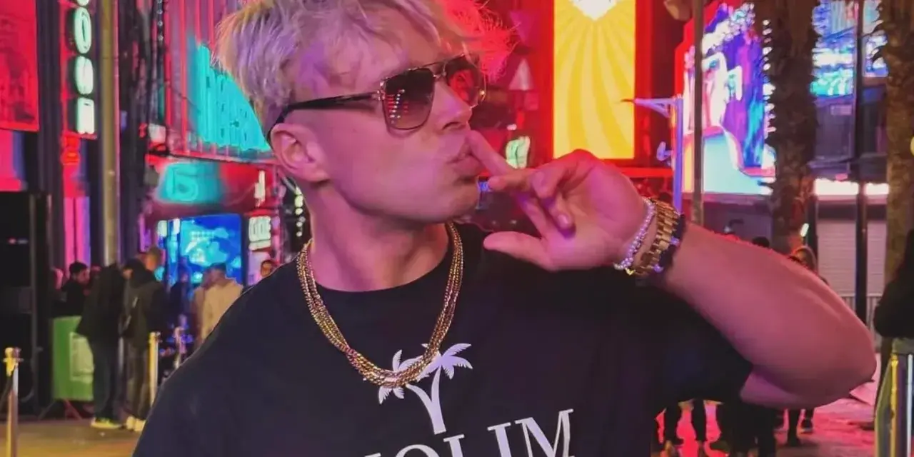 Skolim w okularach i złotych łańcuchach, pozuje na tle neonów. Król Latino w swoim wieku, w blasku miasta.