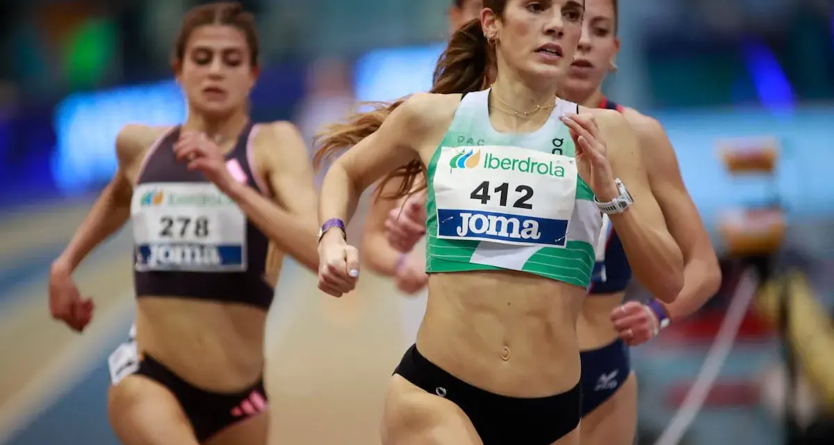 Corredoras en competición de atletismo femenino España. La atleta con el dorsal 412 lidera la carrera, mostrando su determinación.