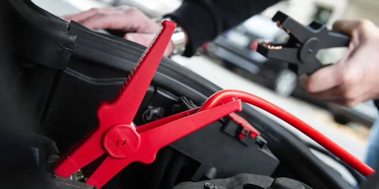 Rotes Kabel mit Krokodilklemme wird an Autobatterie angeschlossen. Plus oder Minus?