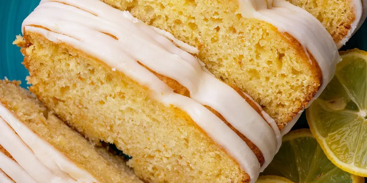 Saftiger Zitronenkuchen mit Zuckerguss, perfekt für einen sonntagskuchen schnell und einfach. Dazu frische Zitronenscheiben.