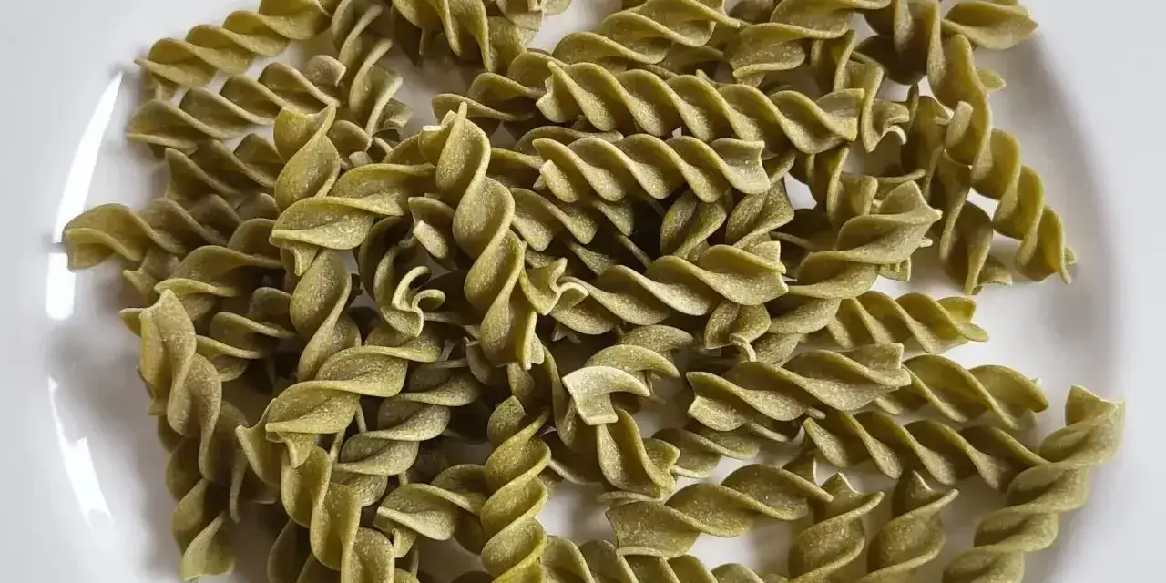 Zielony makaron fusilli z zielonego groszku, gotowy do przygotowania pysznego dania.