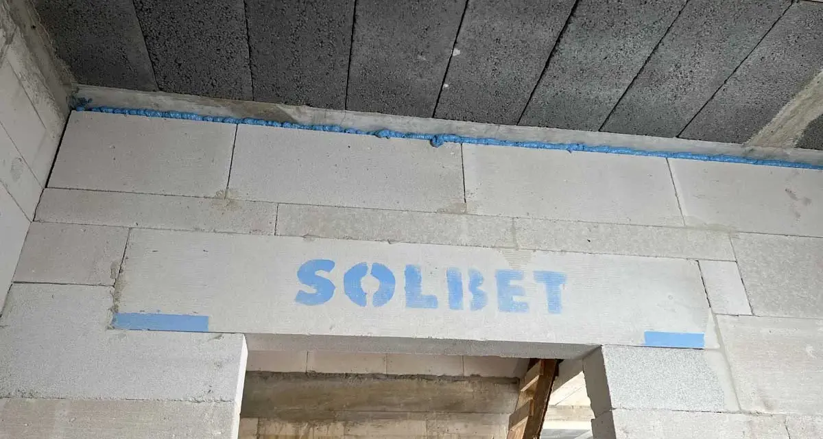 Dylatacja co to? Widoczna szczelina wypełniona pianką między betonem a bloczkami z napisem SOLBET.