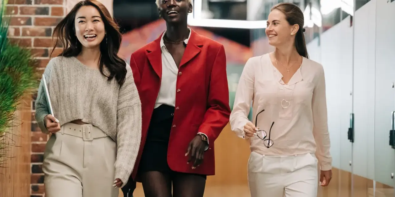 Drei Frauen gehen lachend durch einen Flur. Sie suchen vielleicht Praxissemester Stellen.