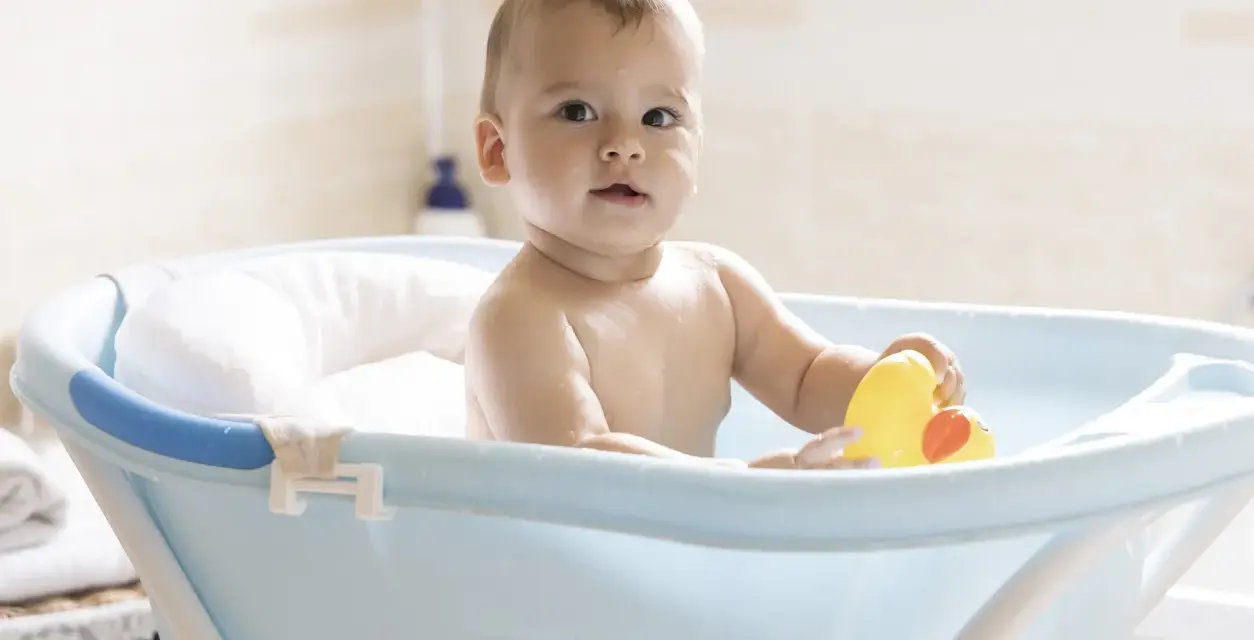 Urocze dziecko w niebieskiej wanience z żółtą kaczką. Kąpiel w wanience jest świetną zabawą, a dziecko może w niej przebywać, dopóki nie zacznie samodzielnie siadać i wstawać.