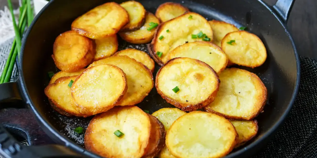 Goldbraune Bratkartoffeln mit Salz und Schnittlauch in einer Pfanne. Ein einfaches Bratkartoffeln Rezept für jeden Tag.