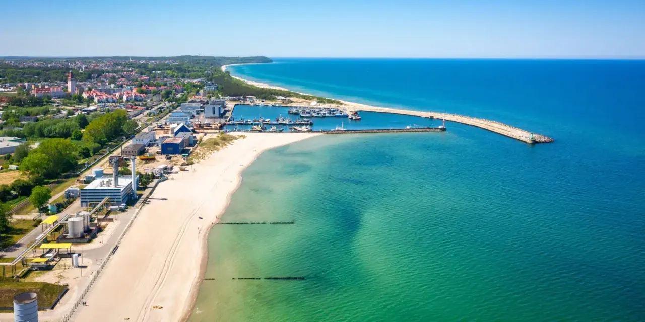 Słoneczna plaża Władysławowo z portem i turkusową wodą Bałtyku.