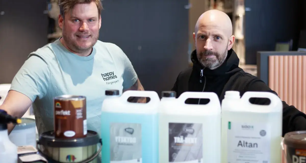 Två män presenterar produkter för att lasera altan. En burk med träolja och flera flaskor med rengöring och skydd.