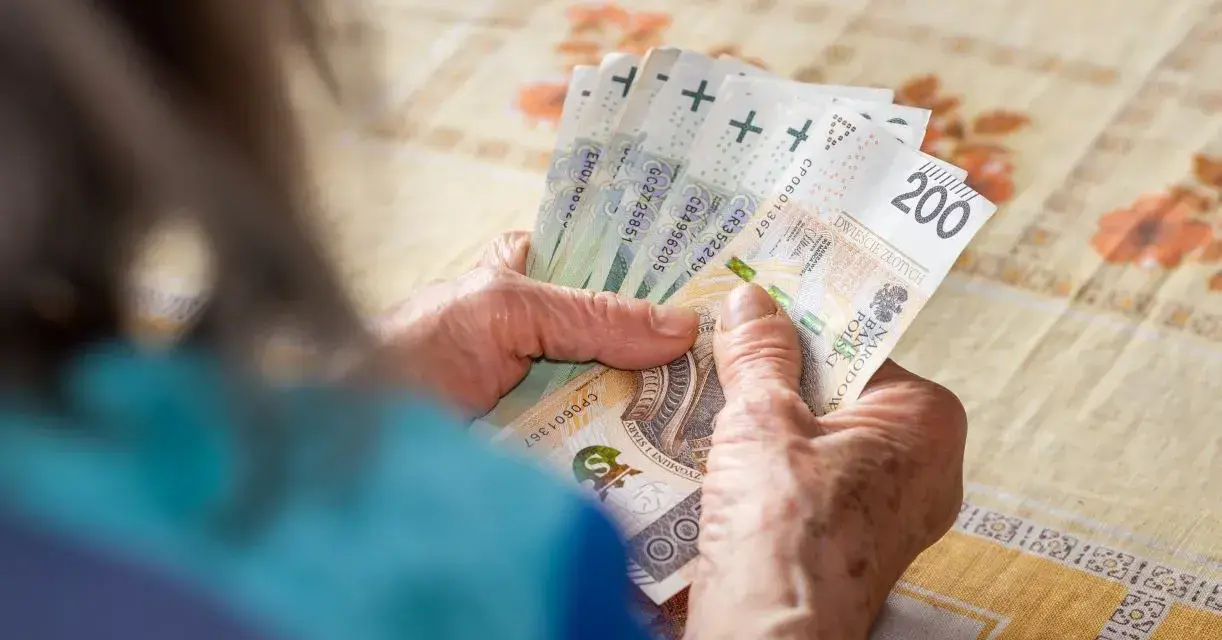 Dłonie starszej osoby liczą banknoty 200 zł. Może to być związane z drugą waloryzacją emerytur, która poprawia byt seniorów.