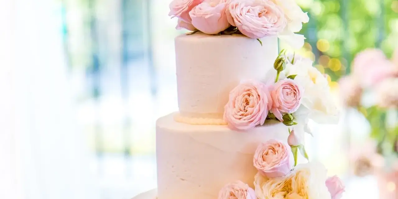 Elegancki tort weselny glamour ozdobiony delikatnymi różowymi i kremowymi różami.