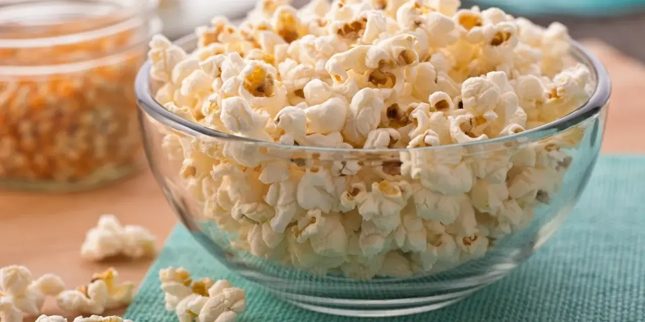 Misternie ułożony popcorn w szklanej misce. Czy popcorn jest zdrowy? To zależy od sposobu przygotowania, ale sam w sobie jest dobrym źródłem błonnika.