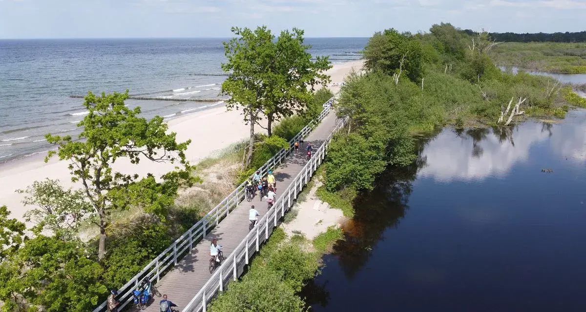 Rowerzyści przemierzają malowniczą trasę EuroVelo 10 wzdłuż plaży i spokojnej wody.