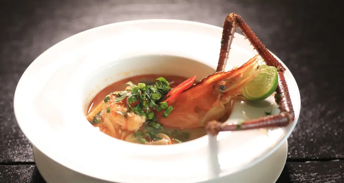 Sopa de marisco con gamba, lima y chile en plato blanco.