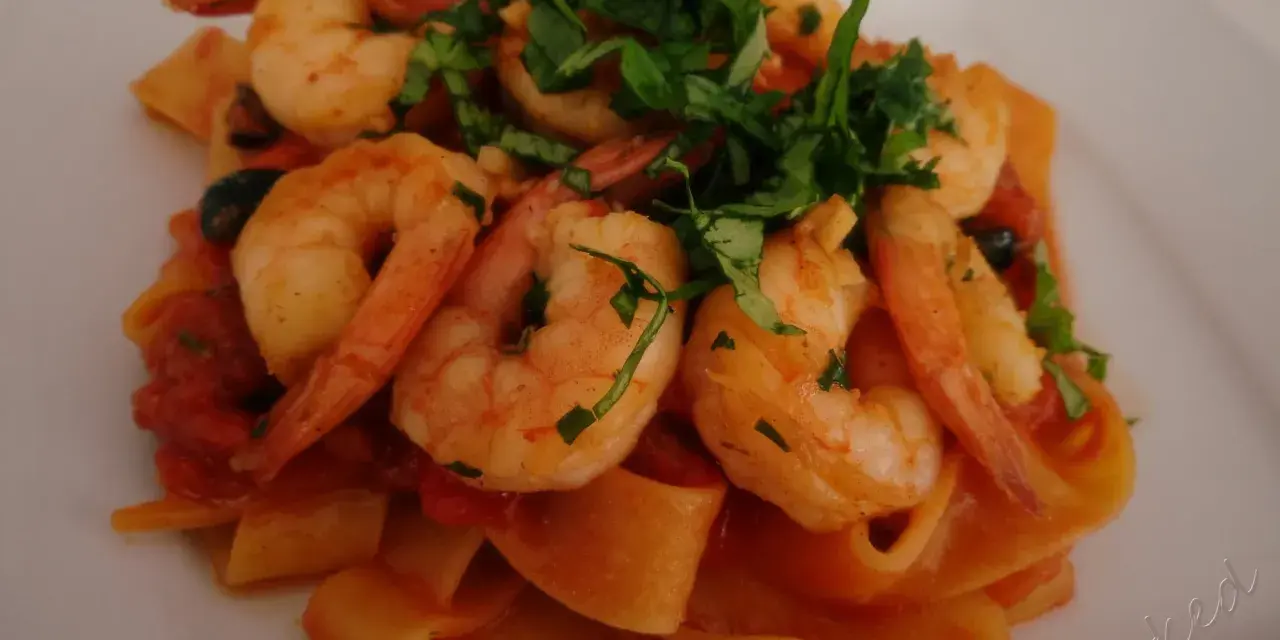 Pappardelle z krewetkami i pomidorkami, posypane świeżą natką pietruszki. Pyszne danie, które zachwyci każdego smakosza.