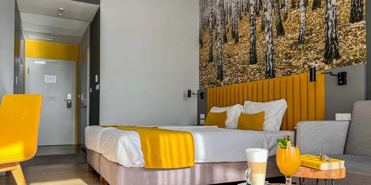Pokój hotelowy z motywem lasu, żółtym akcentem i napojami. Idealne miejsce na relaks, jak sugerują notera hotel spa opinie.