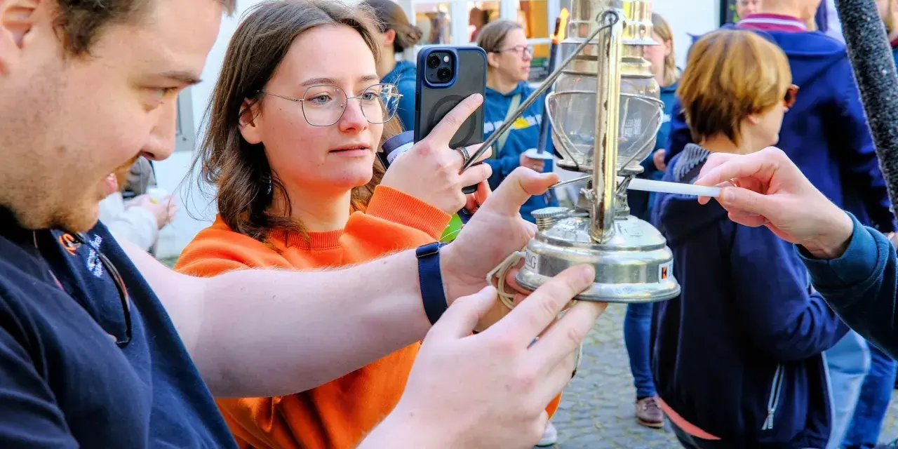 Eine Frau hält ein Handy, während eine Kerze das altenberger licht entzündet.