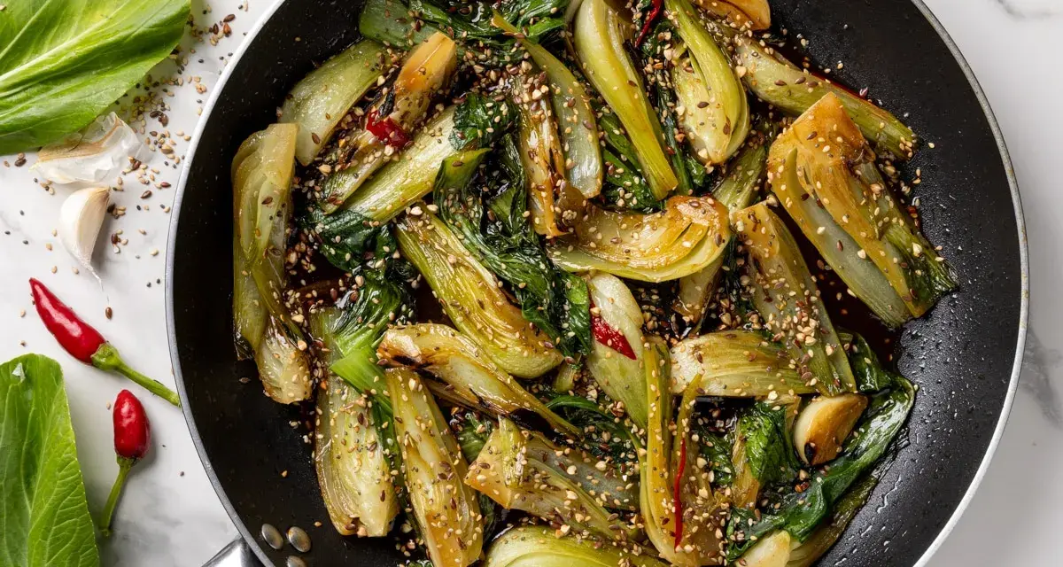 Verdure in padella, bok choy saltato con aglio, peperoncino e semi di sesamo, un piatto saporito e colorato.