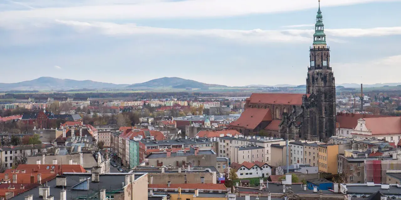 Widok na Świdnicę z górującą nad miastem wieżą katedry. W oddali widać góry. To jedne z głównych świdnica atrakcje.