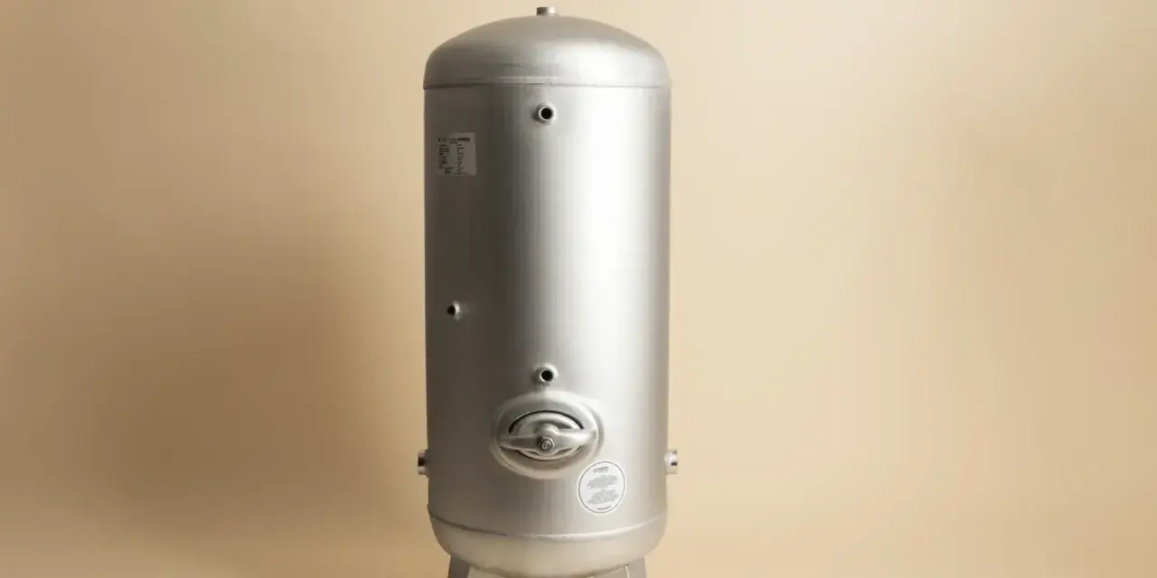 En silverfärgad hydrofor eller hydropress står på tre ben mot en ljusbeige bakgrund.