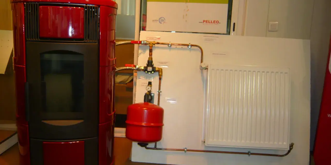 Poêle à granulé hydro rouge connecté à un radiateur blanc. Le système de chauffage est prêt.