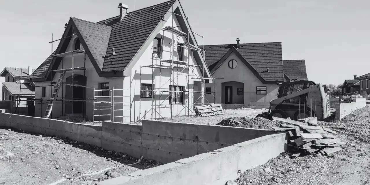 Domy w budowie, rusztowania, koparka i materiały budowlane. Mam pozwolenie na budowę, co dalej? Czas na realizację marzeń o własnym domu.