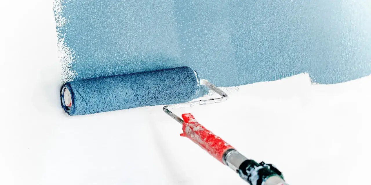 Rouleau à peinture bleu appliquant une bande de couleur sur un mur blanc. L'outil est prêt pour peindre.