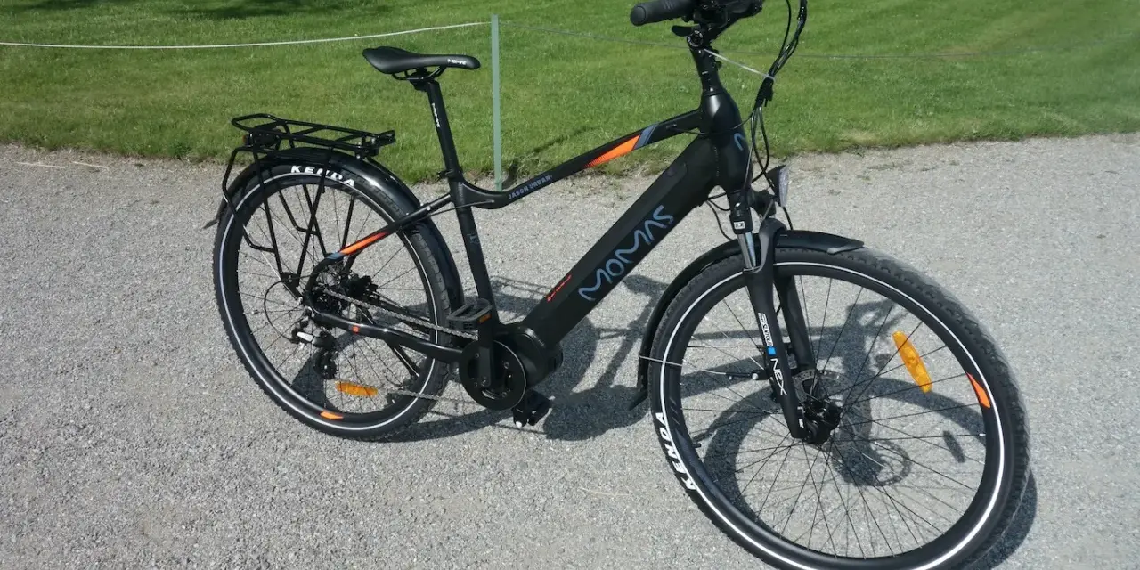 Svart elcykel, modell MOMAS JASON URBAN, redo för ett momas elcykel test. Ställning bak, skärmar och reflexer syns tydligt.