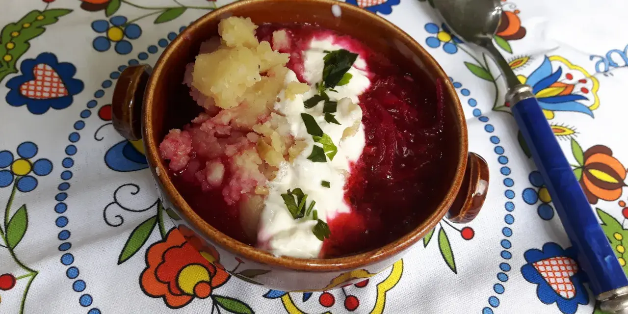 Pyszny przepis na barszcz czerwony z ziemniakami, podany z kleksem śmietany i posypany szczypiorkiem. Idealny na chłodne dni.