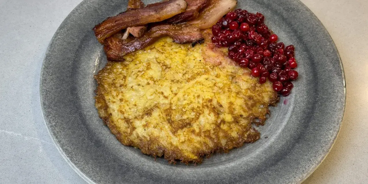 En tallrik med raggmunk, stekt fläsk och lingon. Ett klassiskt svenskt raggmunk recept som är perfekt för en mysig middag.