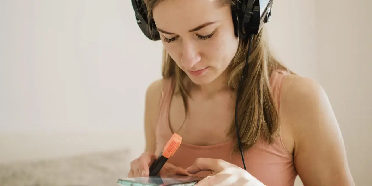 Dziewczyna w słuchawkach przegląda spotify lyrics na telefonie, zaznaczając fragmenty pomarańczowym pisakiem.