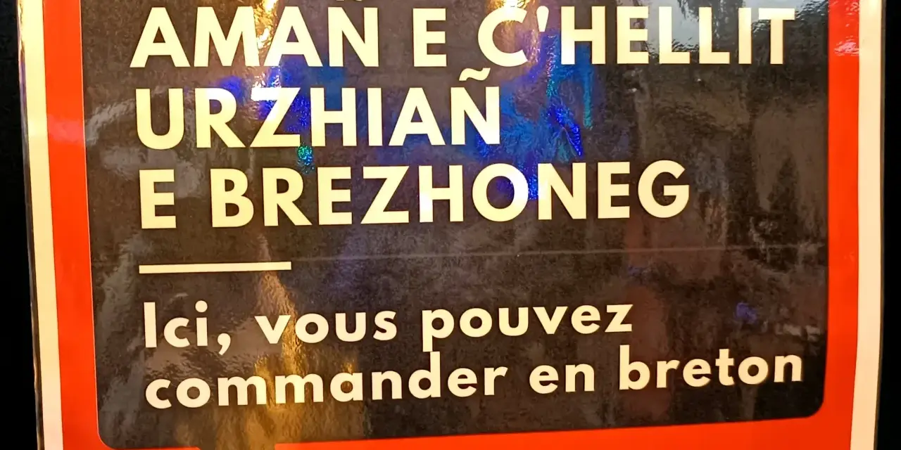 Cartel en bretón y francés: "Aquí puedes pedir en bretón". Un festival en Bretaña, Francia.