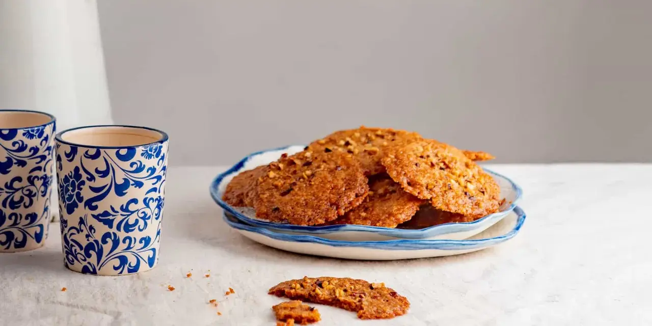 Deliciosas galletas de jengibre con trocitos de nuez, servidas en un plato azul y blanco.