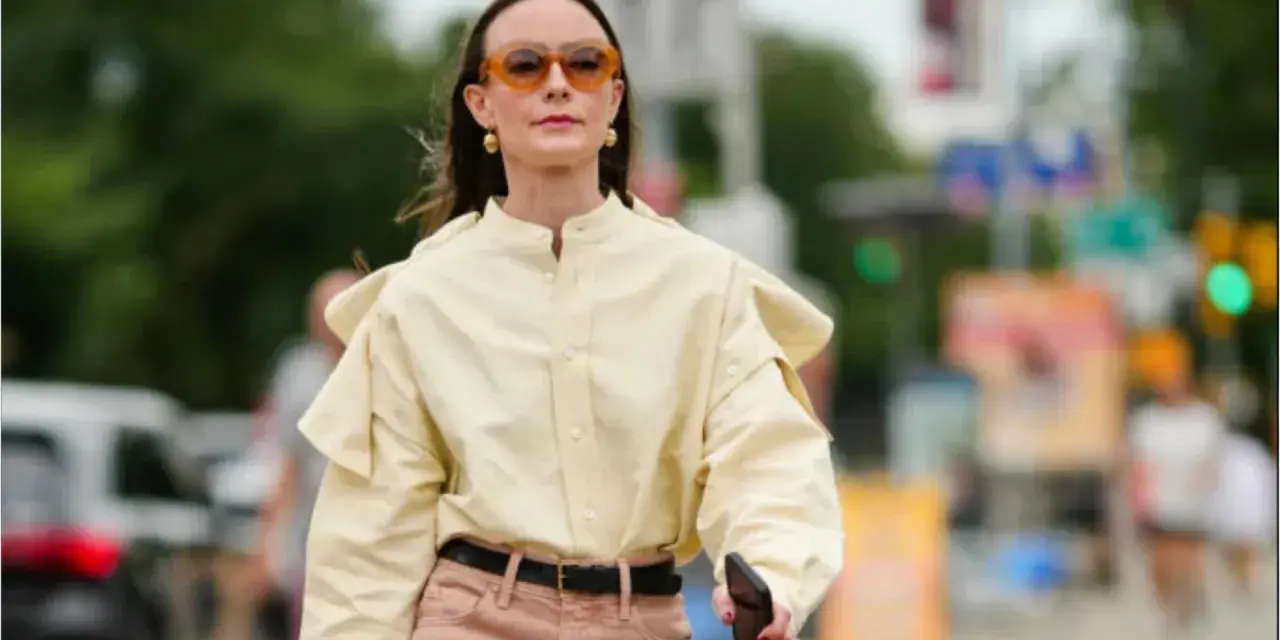 Donna con camicia gialla e pantaloni rosa. Un esempio di pantaloni rosa abbinamenti perfetti per un look casual chic.
