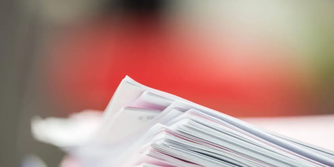 Stos dokumentów, potencjalne dowody rzeczowe w postępowaniu karnym, z czerwonym tłem.