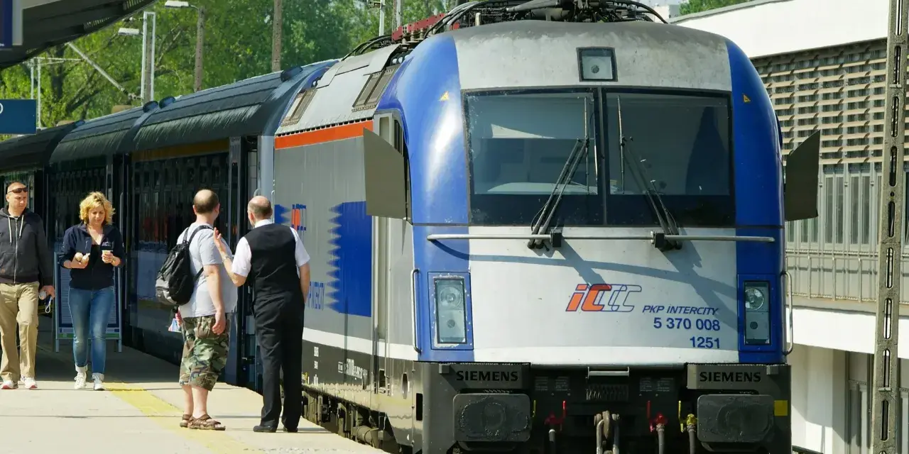 Pasażerowie czekają na pociąg PKP Intercity, gotowi do podróży z biletem wakacyjnym.