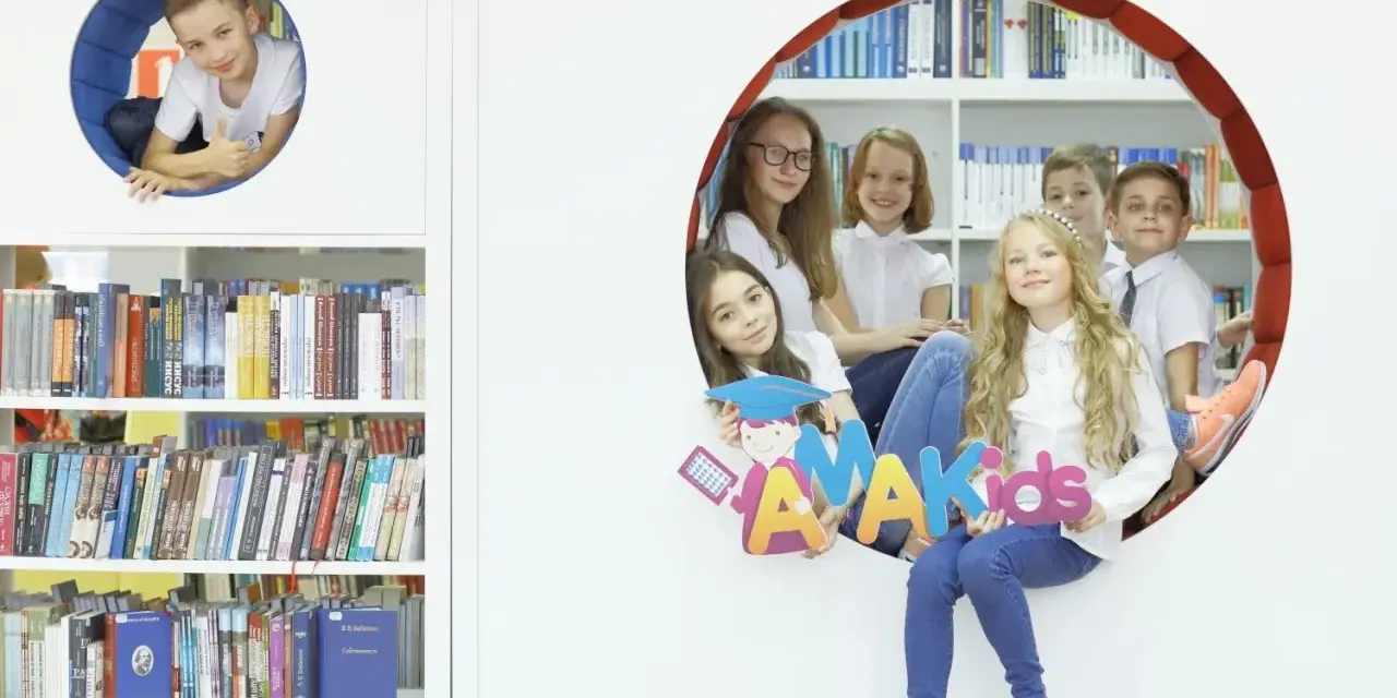 Dzieci z radością pozują z literami "AMAKids" w bibliotece.