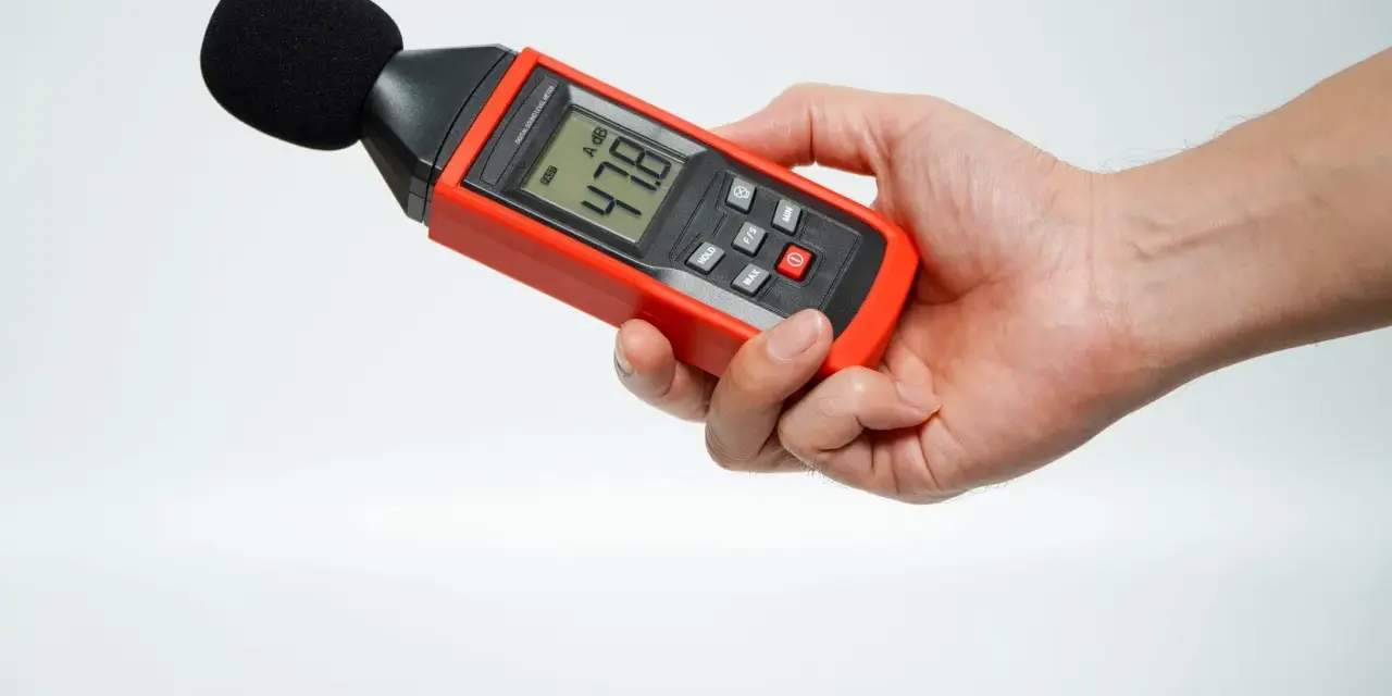 Main tenant une sonomètre pour savoir comment mesurer les décibels dans une pièce. L'appareil affiche 47.8 dB.
