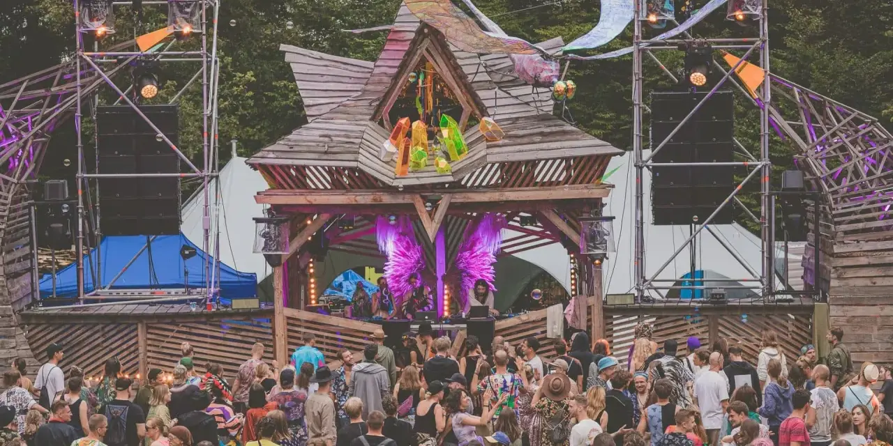 Tłum ludzi na festiwalu **summer contrast festival**. Drewniana scena z dekoracjami, głośniki i światła tworzą magiczną atmosferę.