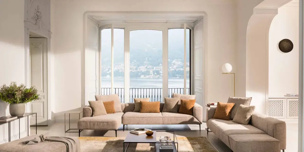 Un salon cocooning chaleureux avec un grand canapé d'angle, des coussins douillets et une vue imprenable sur un lac.