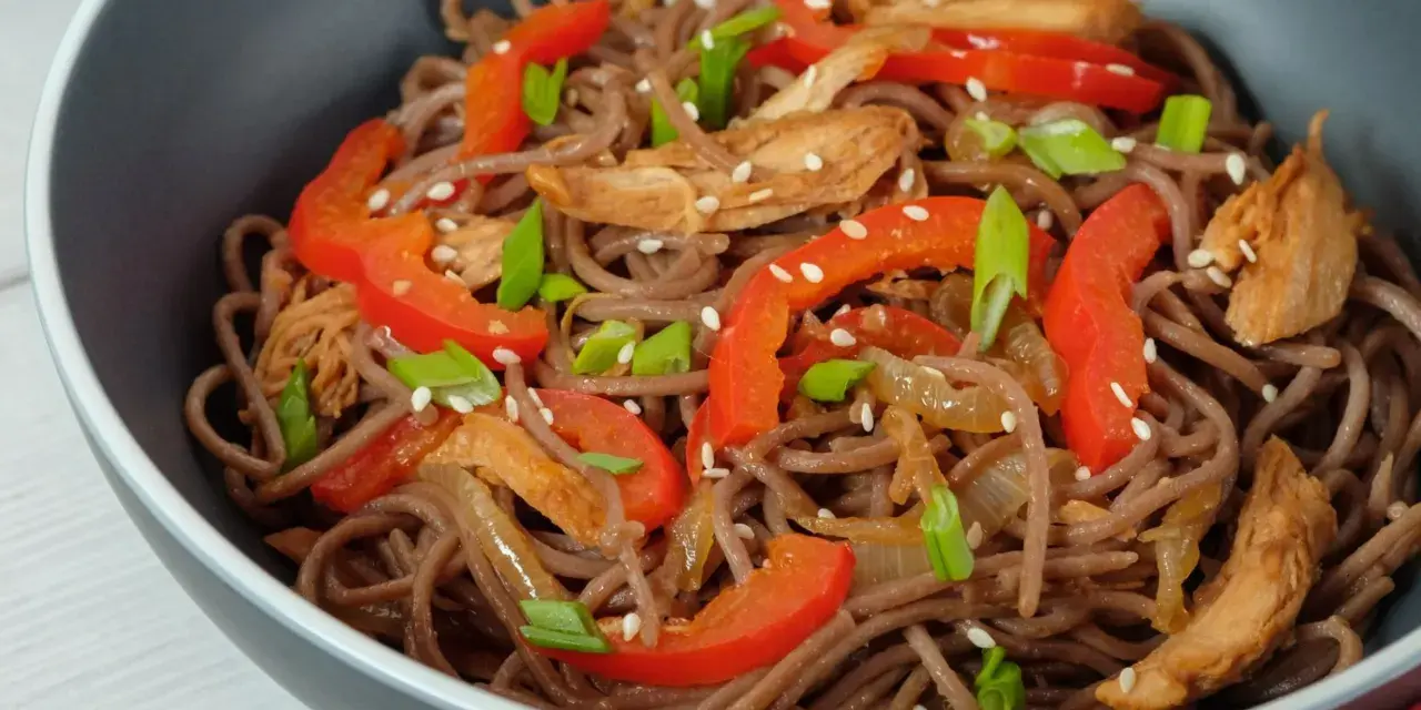 Makaron soba przepis: danie z makaronem gryczanym, kurczakiem, papryką i szczypiorkiem, posypane sezamem.